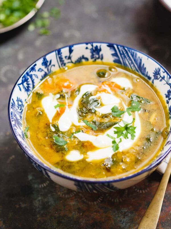 Iransk-inspirert gul suppe med spinat i mønstret bolle på mørk bakgrunn, sett tett på
