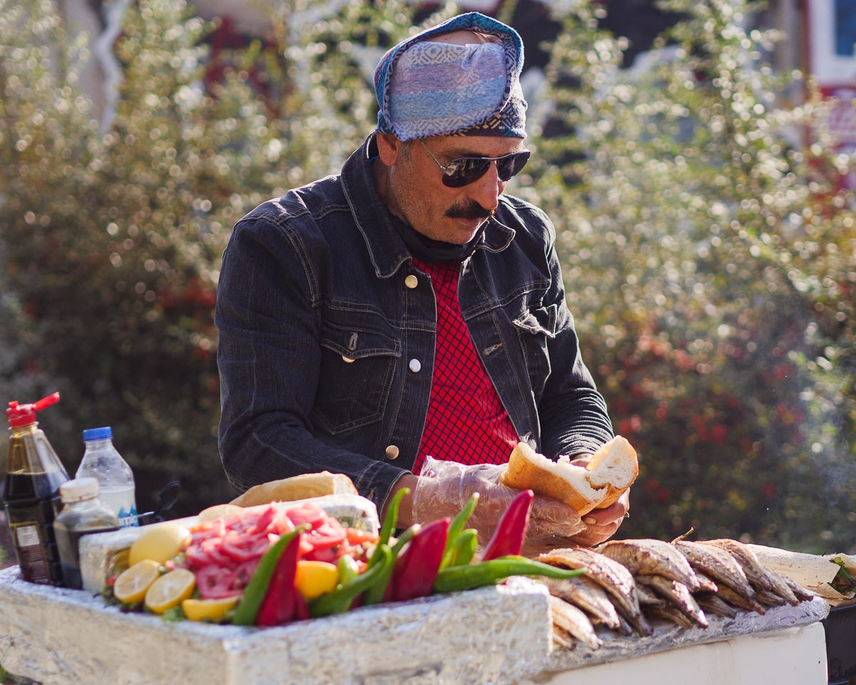 Mann som lager fiskesandwich på gata i Istanbul