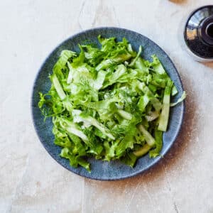 Grønn salat med milde smaker på fat og lys bakgrunn, sett ovenfra