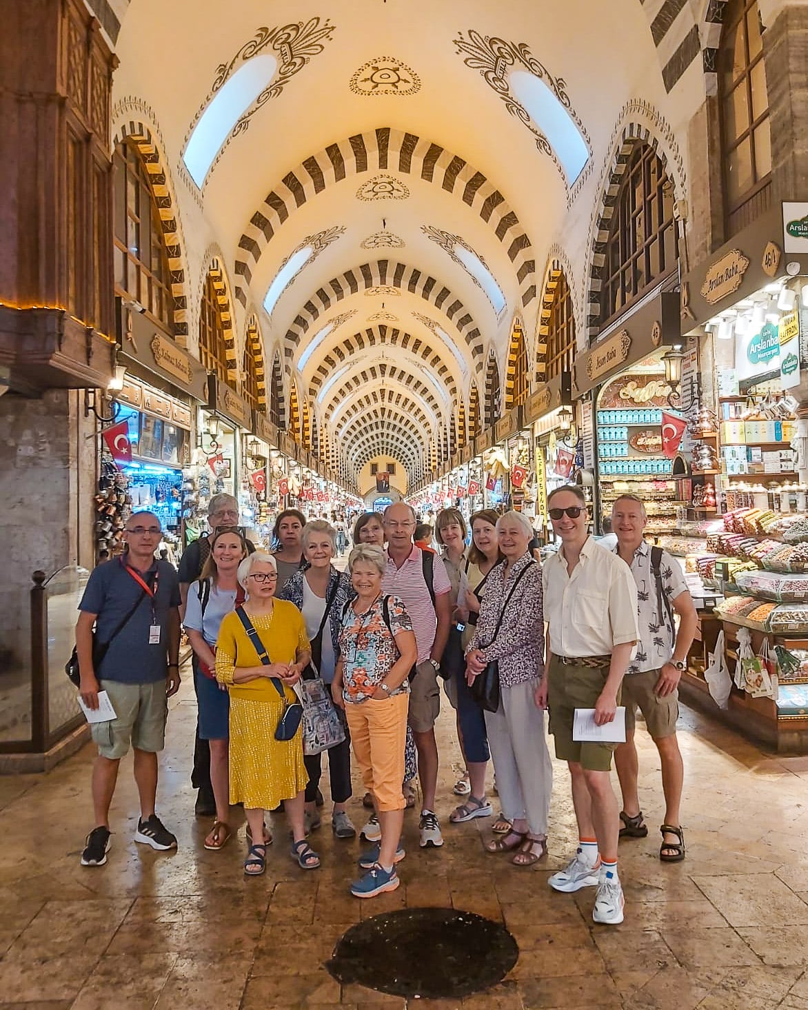 En gruppe nordmenn i krydderbasaren i Istanbul, med det praktfulle bygget i bakgrunn og bodene på sidene.