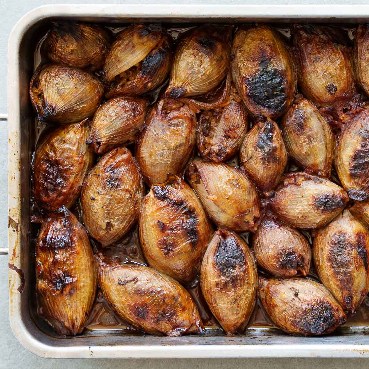 Ovnsbakte fylte løk (soğan dolması) med mørke stekeflekker, tett i tett i en ildfast form